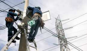 Trabajadores de la Comisión Federal de Electricidad reparan un poste de luz