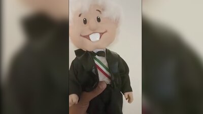 Este 'souvenir' porta un pantalón negro, una camisa blanca, con la banda presidencial