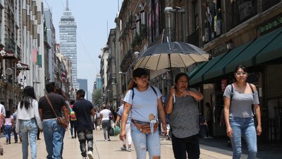 Ciudadanos intentan mitigar el calor con sombrillas y tomando agua