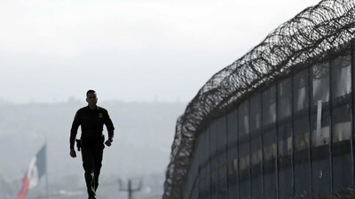 Un agente de la Patrulla Fronteriza vigila una barrera que divide a EU de México