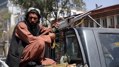 Un combatiente del Talibán apostado con una ametralladora frente al principal ingreso al palacio presidencial en Kabul