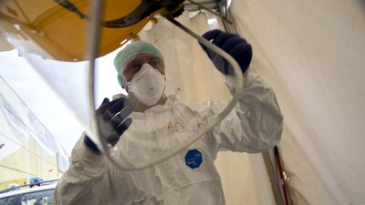 Un enfermero italiano coloca equipo protector para facilitar el traslado de pacientes de COVID-19