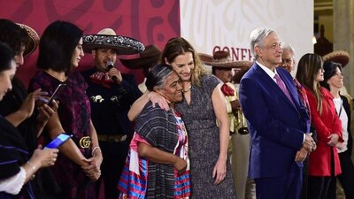 Beatriz Gutiérrez (centro) abraza a una madre en el festejo que presidió AMLO