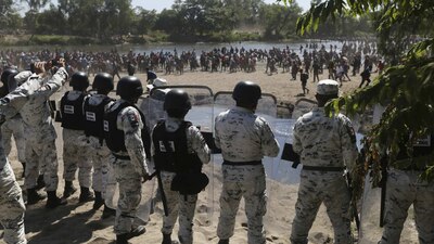 Elementos de la Guardia Nacional parados en la orilla el río Suchiate en donde centroamericanos cruzan desde Guatemala