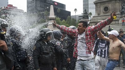 Un aficionado rocía de espuma a policías de la Ciudad de México luego del triunfo de México