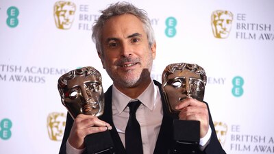 El mexicano Alfonso Cuarón sosteniendo dos de los 4 premios Bafta que ganó este domingo