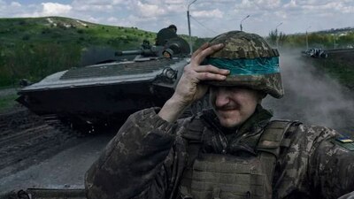 Un soldado de Ucrania se agarra el casco mientras viaja a bordo de un APC en Bájmut