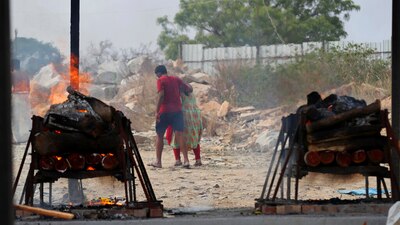 Familiares de víctimas del COVID-19 se marchan mientras sus piras funerarias arden en un crematorio al aire libre